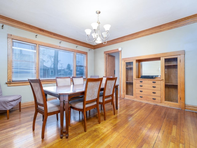 dining room with an inviting chandelier, crown molding, and light wood-style floors