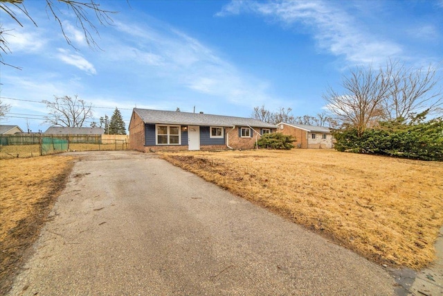 ranch-style home featuring aphalt driveway and fence