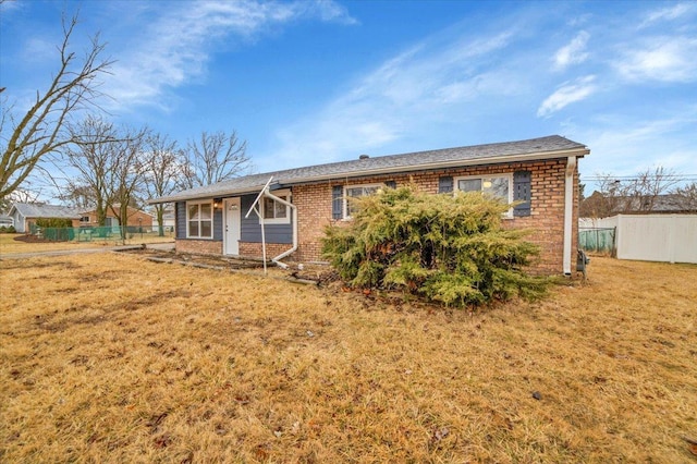 ranch-style house featuring a front yard, brick siding, and fence