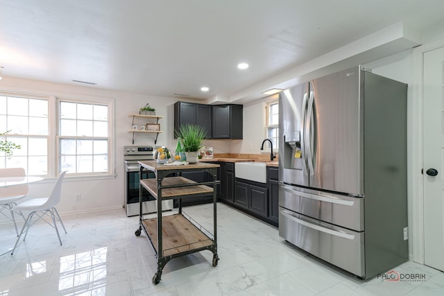 kitchen featuring marble finish floor, stainless steel appliances, a sink, and a wealth of natural light