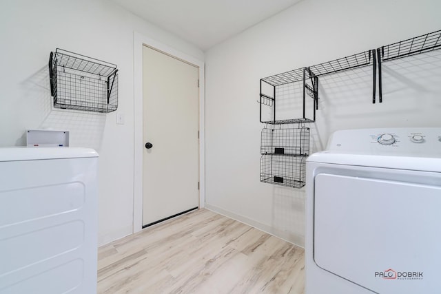 washroom featuring laundry area, light wood-type flooring, and washing machine and dryer