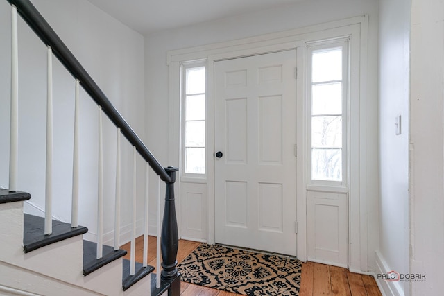 foyer with light wood finished floors, stairway, and plenty of natural light