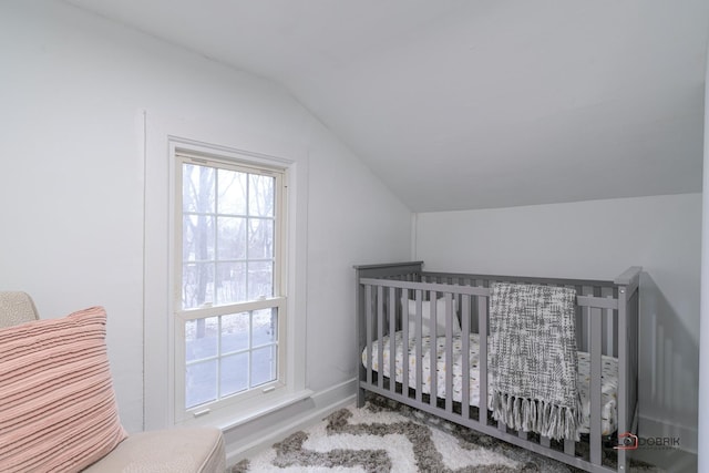 bedroom featuring lofted ceiling, a nursery area, and baseboards