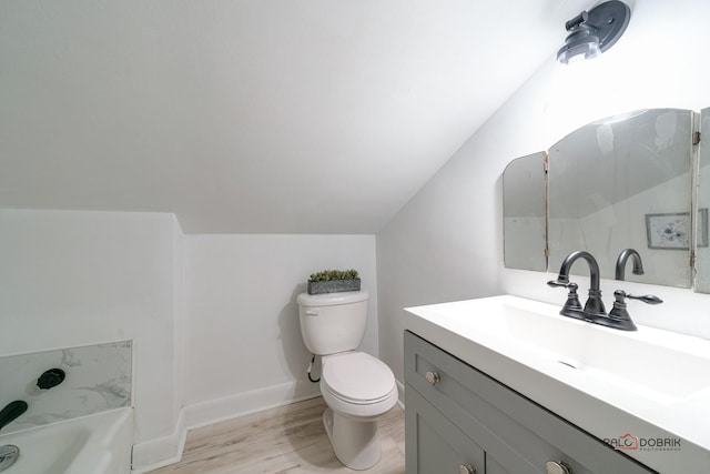 bathroom with lofted ceiling, toilet, a washtub, wood finished floors, and vanity