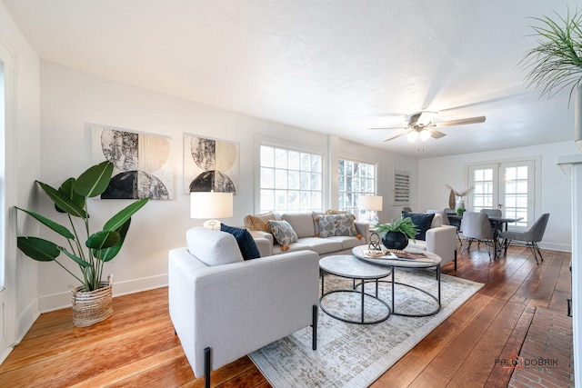 living room featuring french doors, baseboards, ceiling fan, and hardwood / wood-style floors