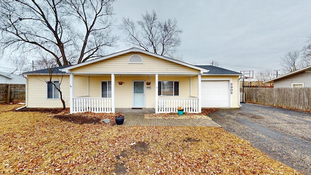 view of front of home with aphalt driveway, a porch, a garage, and fence