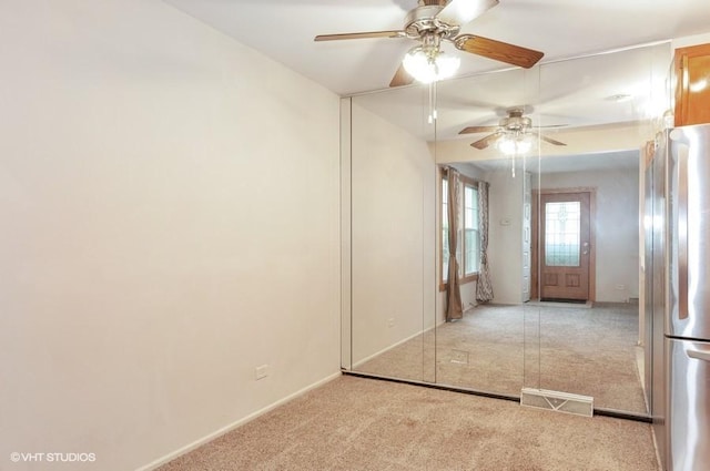 unfurnished room with carpet, visible vents, and ceiling fan