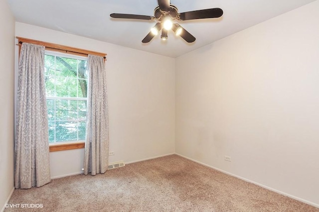 carpeted spare room featuring a ceiling fan, baseboards, and visible vents