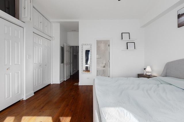 bedroom featuring dark wood-style floors, baseboards, and multiple closets