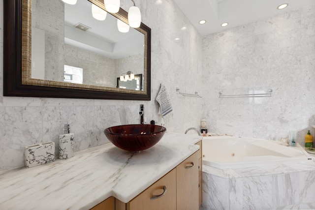 full bathroom featuring visible vents, a jetted tub, vanity, tile walls, and recessed lighting