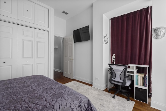 bedroom featuring baseboards, a closet, visible vents, and wood finished floors