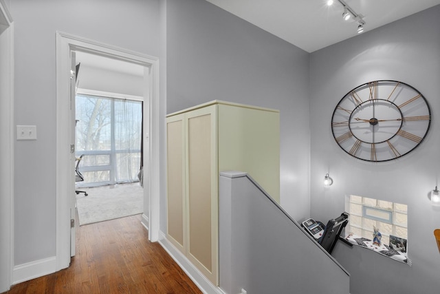 hall featuring track lighting, baseboards, an upstairs landing, and wood finished floors