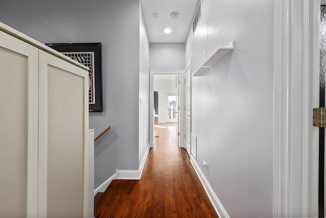 hallway with an upstairs landing, wood finished floors, visible vents, and baseboards