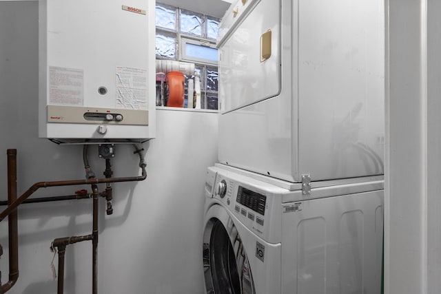 clothes washing area with laundry area, tankless water heater, and stacked washer / drying machine