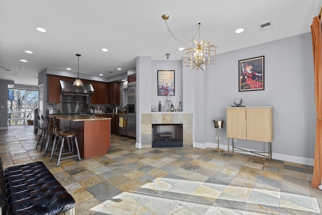 kitchen featuring a breakfast bar, stone tile floors, recessed lighting, visible vents, and baseboards