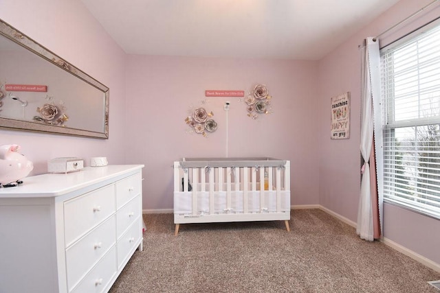 unfurnished bedroom with a nursery area, carpet, and baseboards