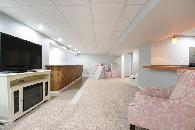 interior space featuring baseboards, a glass covered fireplace, light colored carpet, a paneled ceiling, and recessed lighting