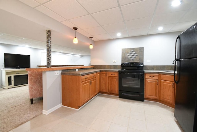 kitchen with dark countertops, brown cabinets, a peninsula, and black appliances