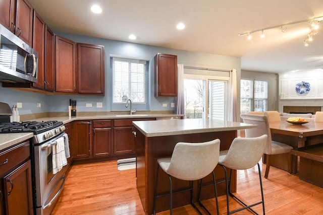 kitchen with a breakfast bar area, stainless steel appliances, a kitchen island, a sink, and light wood-style floors