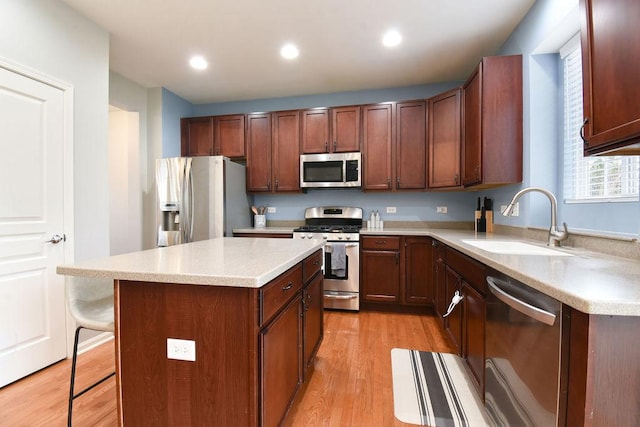 kitchen featuring light wood-style flooring, a center island, stainless steel appliances, light countertops, and a sink