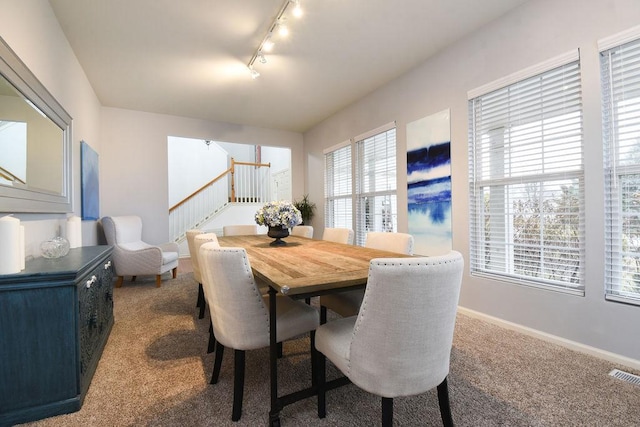 dining space with visible vents, baseboards, stairway, carpet flooring, and track lighting