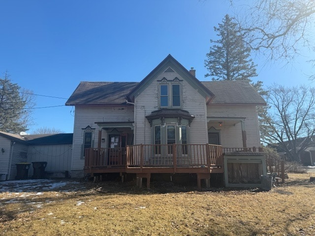 victorian-style house featuring a chimney and a wooden deck