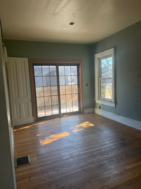 unfurnished room with wood finished floors, visible vents, and baseboards