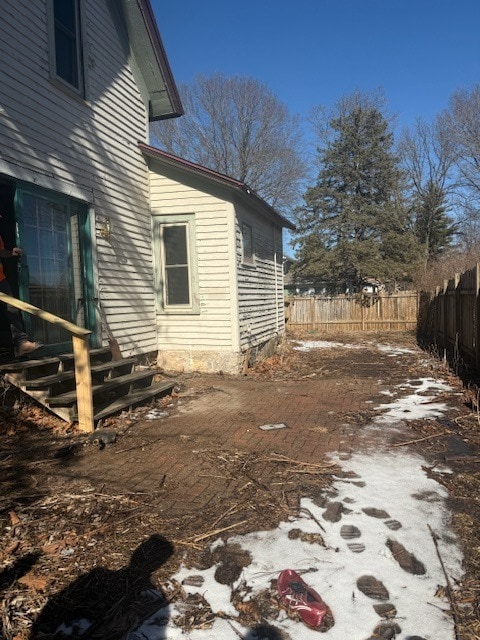 view of side of home with entry steps and fence