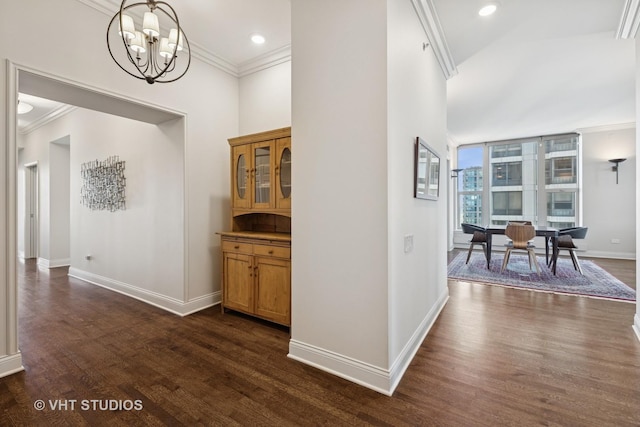 corridor with dark wood finished floors, crown molding, baseboards, and a chandelier