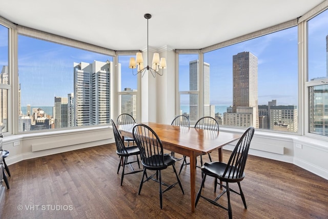 dining area featuring a chandelier, a city view, baseboards, and wood finished floors