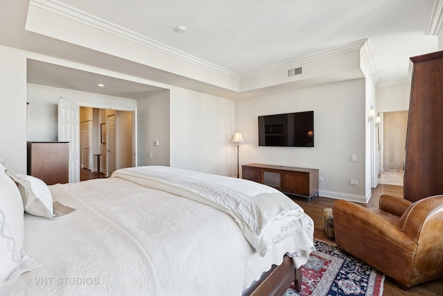 bedroom featuring baseboards, wood finished floors, visible vents, and ornamental molding