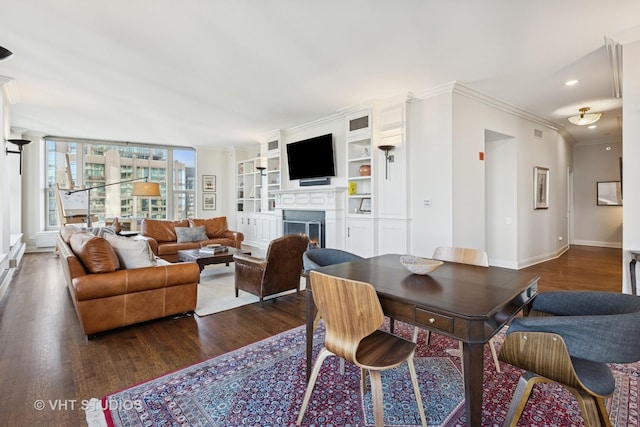 dining space featuring baseboards, a lit fireplace, dark wood finished floors, and crown molding