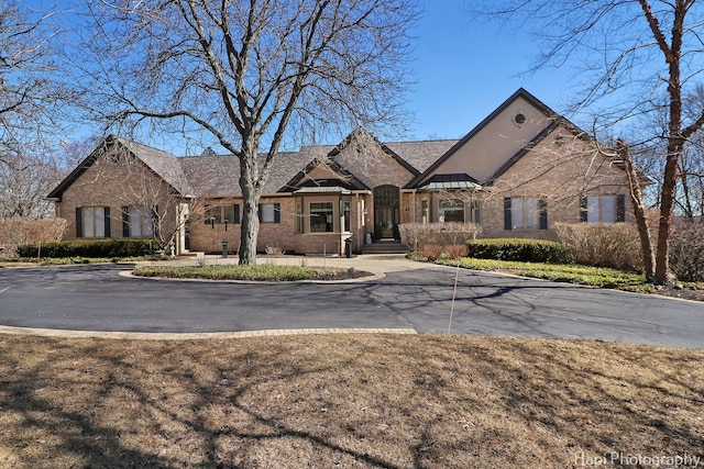 french country home featuring a standing seam roof, brick siding, and metal roof