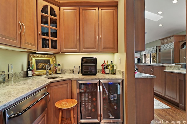 kitchen featuring wood finished floors, light stone countertops, recessed lighting, stainless steel appliances, and wine cooler