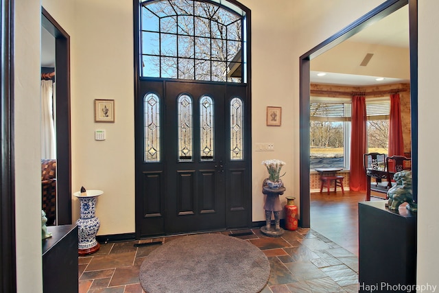 entryway with baseboards and stone tile flooring