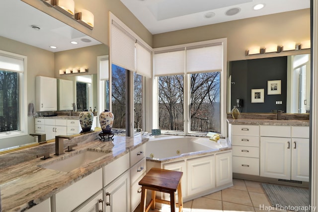 bathroom featuring a sink, a whirlpool tub, two vanities, and tile patterned floors