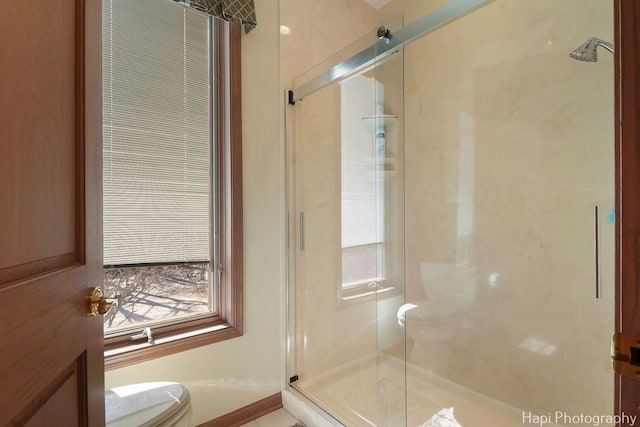 bathroom with a shower stall, toilet, and a healthy amount of sunlight