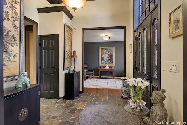 foyer with stone tile floors and baseboards