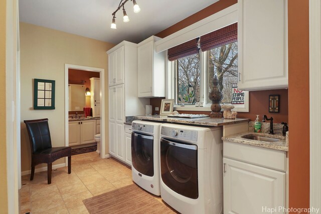 laundry area with cabinet space, independent washer and dryer, light tile patterned flooring, and a sink