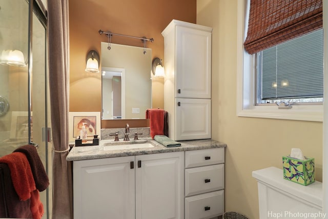 bathroom with a shower with door, toilet, and vanity