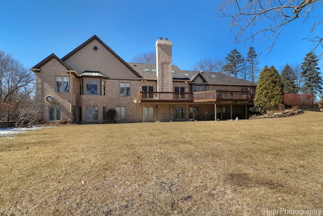 back of house featuring a deck, a yard, brick siding, and a chimney