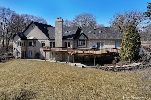 rear view of house featuring a wooden deck, a lawn, a chimney, and a patio area