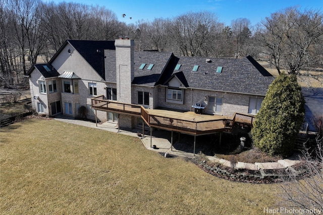 rear view of house featuring a patio, a yard, a chimney, and a wooden deck