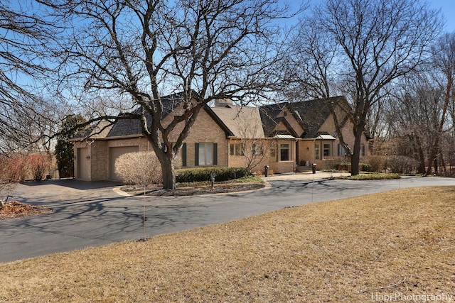 view of front of house with aphalt driveway, an attached garage, and brick siding