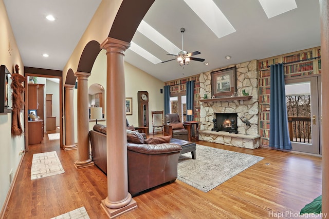 living room with lofted ceiling, decorative columns, a fireplace, wood finished floors, and a ceiling fan