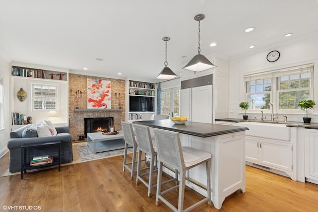 kitchen with white cabinetry, light wood-style floors, a kitchen bar, and a sink