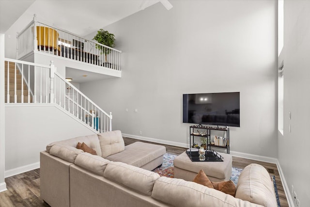 living area featuring stairway, a high ceiling, baseboards, and wood finished floors