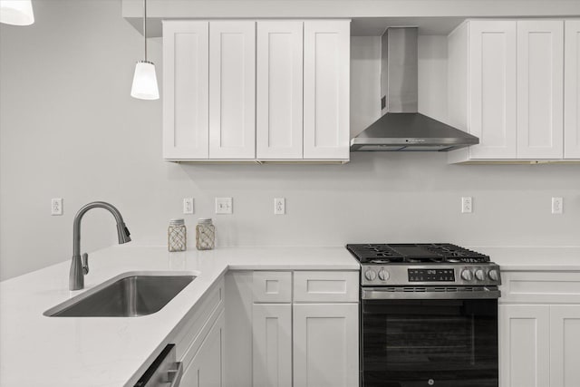 kitchen with stainless steel gas range oven, white cabinetry, wall chimney range hood, and a sink