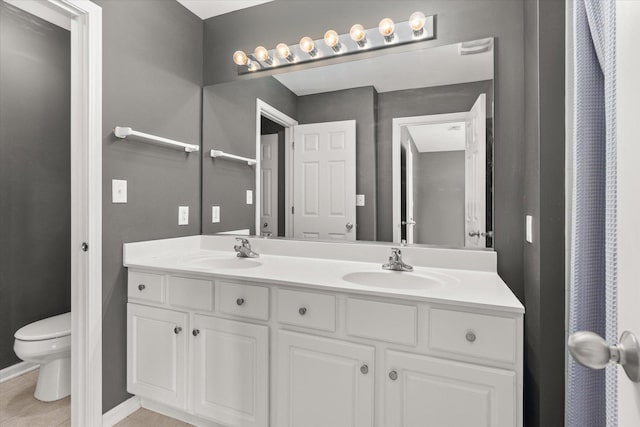 full bathroom featuring double vanity, tile patterned flooring, toilet, and a sink