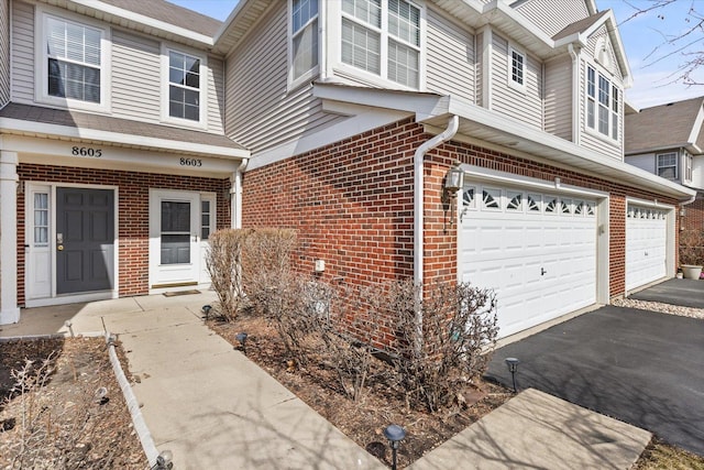 view of front of property featuring aphalt driveway, a garage, and brick siding